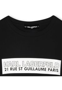 Μαύρο βαμβακερό T-shirt με στρογγυλή λαιμόκοψη, με λευκή εκτυπωμένη επιγραφή: "KARL LAGERFELD 21 RUE ST GUILLAUME PARIS." Η ετικέτα υποδηλώνει μέγεθος "παιδικό".