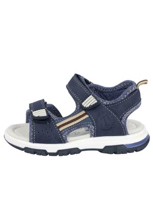 Sandalia azul marino con correas ajustables, parte superior texturizada, suela acolchada blanca y acentos de raya marrón. Presenta un diseño perforado para transpirabilidad.