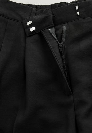 Czarne spodnie z dopasowanym pasem, zapięciem na zamek błyskawiczny i dwoma metalowymi guzikami. Charakteryzują się plisowanymi detalami i gładką fakturą tkaniny.