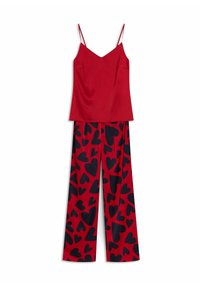 Red satin camisole with thin straps paired with wide-leg trousers in red and navy blue heart pattern. Smooth fabric and relaxed fit.