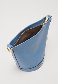 Borsa a secchiello in pelle blu con una cerniera dorata, texture liscia e un accento dorato con il marchio alla base. Design con apertura superiore.