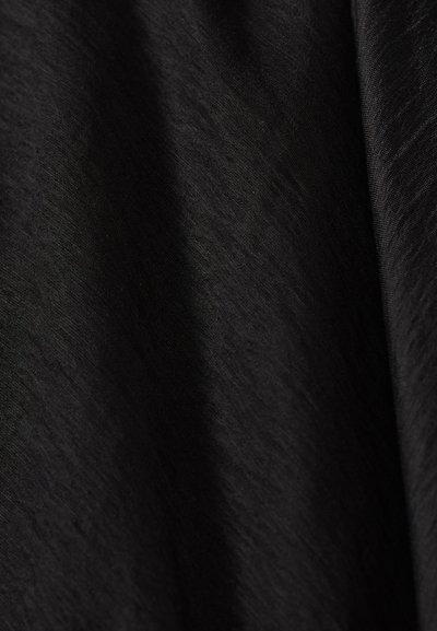 Gros plan d’un tissu noir doux avec des plis subtils et une surface lisse légèrement texturée.