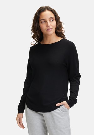 Black long-sleeve sweater with a crew neck, smooth texture, loose fit, and ribbed cuffs, paired with light gray sweatpants.