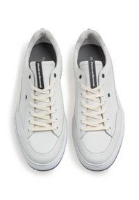 Sneakers bianchi in pelle con lacci color crema, suola piatta, punta rotonda e design minimale. Presentano una linguetta con logo e dettagli cuciti.