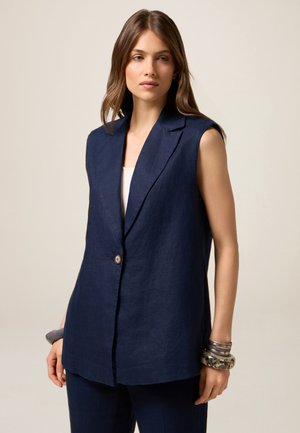 Blazer senza maniche di colore navy realizzato in lino, dotato di colletto a rever e chiusura con un solo bottone. Texture liscia con vestibilità sartoriale.
