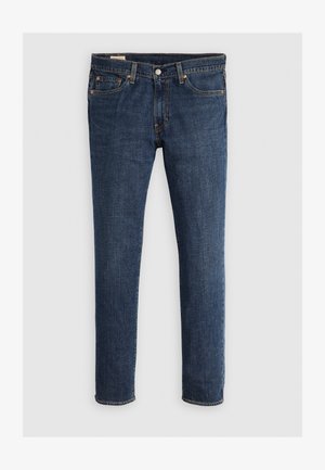 Jeans en denim bleu foncé avec un style classique à cinq poches, rivets en cuivre, fermeture à bouton et coupe droite sur fond uni.