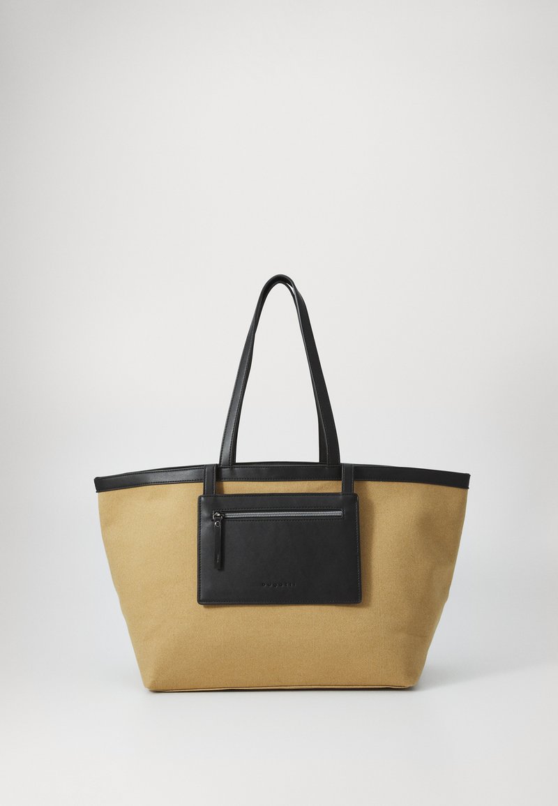 Bolso tote grande hecho de lona beige con acentos de cuero negro, que cuenta con dos asas largas y un bolsillo frontal con cremallera.