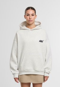 Felpa con cappuccio grigia chiara realizzata in tessuto morbido, dotata di tasca frontale, polsini a costine e un logo sul petto.