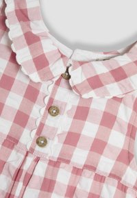 Vestido de cuadros rosa y blanco con un cuello festoneado, dos botones redondos de madera y un detalle de falda plisada. Textura de tela de algodón.