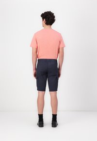 Herremode med en koralfarvet T-shirt og navy cargo shorts. Shortsene har sidelommer og en lige pasform, lavet af letvægtsstof.