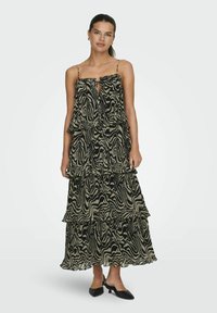 Robe maxi noir et crème à imprimé zèbre, avec des volants, des bretelles spaghetti ajustables et un détail en trou de serrure au niveau du décolleté.