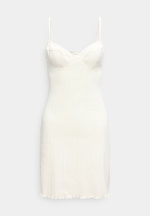 Λευκό μίνι φόρεμα από ριμπ πλεκτό ύφασμα χωρίς μανίκια, με εφαρμοστό μπούστο, V-λαιμόκοψη και λεπτές τιράντες στους ώμους.