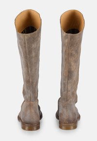 Bottes en cuir marron jusqu'au genou avec une finition texturée, bout rond et talon empilé. Intérieur doublé de matériau beige avec des accents rayés.