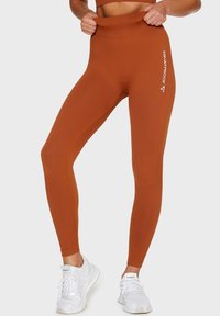 Prążkowane legginsy o wysokim stanie w kolorze spalanej pomarańczy. Charakteryzują się designem odpornym na przysiady oraz białym logo na lewej nogawce. Teksturowana tkanina.