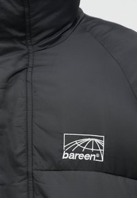 Μαύρο φουστάνι με ψηλό γιακά, επενδεδυμένο με ραμμένα σχέδια και λευκό κεντημένο λογό�τυπο "bareen" στην περιοχή του στήθους. Λείο υφή.