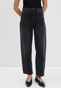 Jeans neri a vita alta e gamba ampia con una texture in denim liscia, dotati di tasche frontali e orlo pulito. Abbinati a scarpe nere.