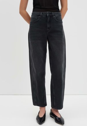 Jeans noirs taille haute à jambes larges avec une texture en denim lisse, dotés de poches latérales et d'un ourlet net. Assortis à des chaussures noires.