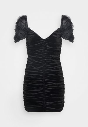 Robe en velours noir avec une coupe ajustée, une texture froncée et des manches bouffantes transparentes. Elle présente un décolleté en V et des détails froncés sur toute la surface.