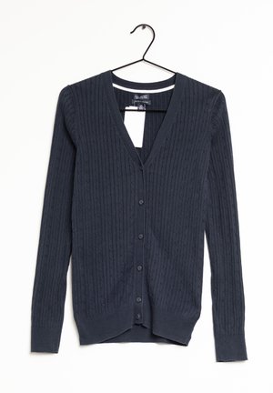 Mørke marineblå kabelstrikket cardigan med lange ærmer, V-hals og knapper foran, hængende på en sort bøjle mod en hvid baggrund.