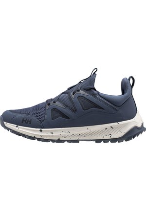 Granatowe buty sportowe z siateczkową cholewką, wyściełanym kołnierzem i białą, plamkowaną podeszwą. Posiadają gumowy bieżnik dla lepszej przyczepności oraz bezpieczny system sznurowania.