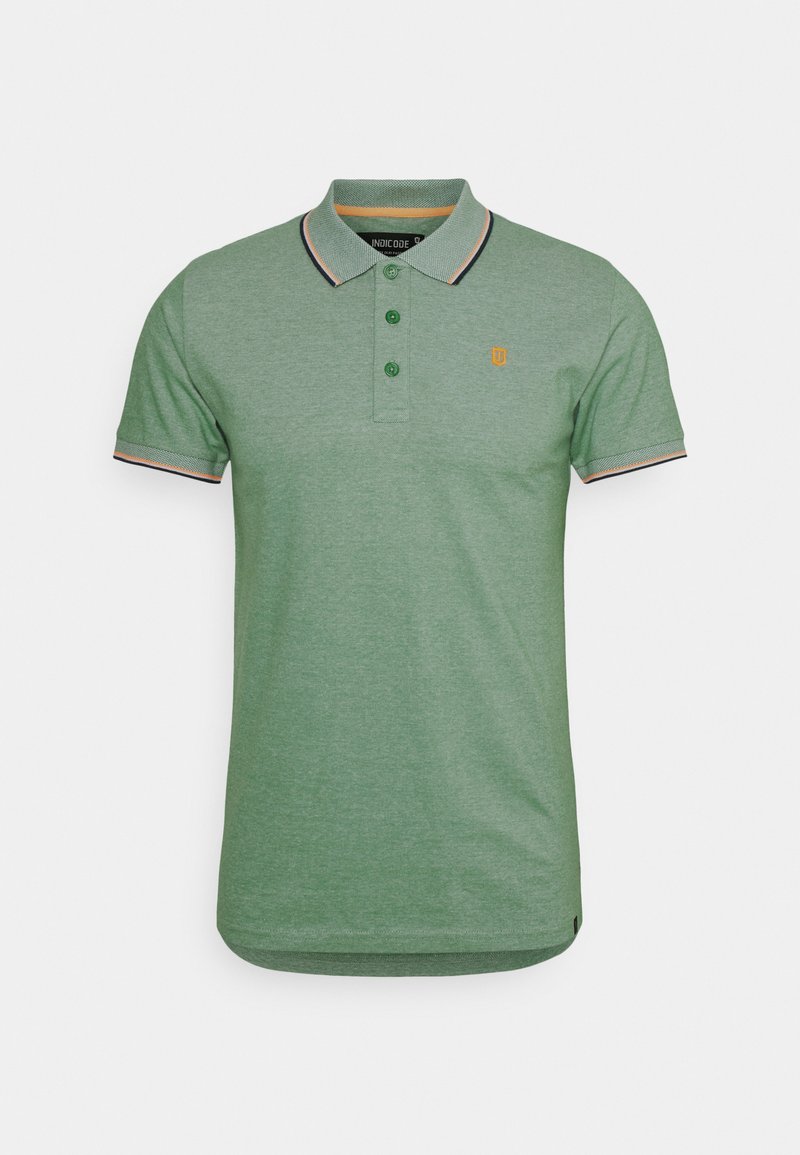 Grønn polo-shirt laget av myk stoff, med krage, tre knapper og korte ermer. Den har kontrasterende stripede detaljer og en logo.