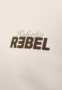 Tekst "Eclectic REBEL" prinditud beežile kangale, kus "REBEL" on trükitud paksus suurte tähtedega ja "E" asemel on pööratud "3".