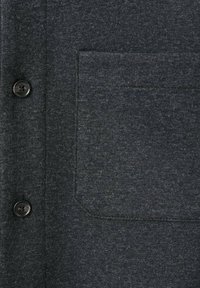 Camicia grigia scura a maniche corte realizzata in tessuto morbido, con due bottoni neri e una tasca sul petto sinistro di forma rettangolare.