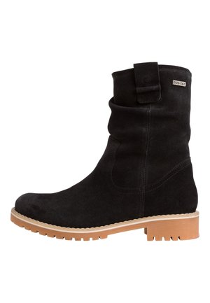 Botte chevillière en suédine noire avec un design drapé, semelle en caoutchouc et talon beige. Elle possède une sangle et un accent de marque sur la tige.