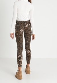 Leggings de estampado de leopardo con corte ajustado, cintura alta y tejido suave. Combinados con una camiseta de manga larga blanca y zapatillas gruesas beiges.