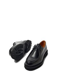 Zapatos de cuero negro con punta redondeada, diseño de cordones y suelas de goma texturizadas con un patrón de agarre para tracción.