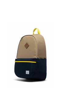 Sac à dos bicolore avec partie supérieure camel, partie inférieure bleu marine, poche frontale zippée avec bordure de fermeture éclair jaune, écusson marron en forme de losange et poignée supérieure jaune.