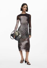 Figurbetontes Kleid mit langen, durchsichtigen Ärmeln, das ein strukturiertes, abstraktes Design in gedämpften Erdtönen zeigt. Kombiniert mit einer kleinen, strukturierten Tasche.