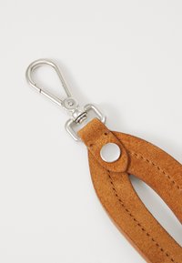 Cinturino in pelle color ambra, dotato di un clip metallico argentato e di un accento circolare argentato. Superficie testurizzata con dettagli di cucitura discreti.