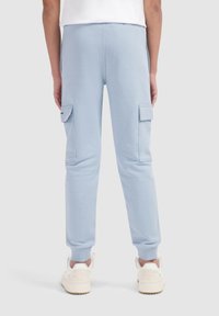 Lichtblauwe cargo sweatpants met zijzakken, taps toelopende boorden en een zachte textuur, gecombineerd met witte sneakers met een dikke zool.