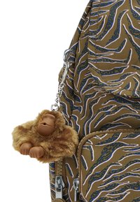 Brun väska med ett vågigt blått och vitt mönster. Har en mjuk apa-nyckelring, med små händer och ett runt ansikte, fäst med en silverklipp.