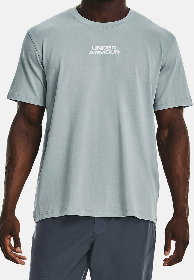 Lyseblå kortærmet t-shirt i blødt stof med en hvid "UNDER ARMOUR"-logo centreret på brystet.