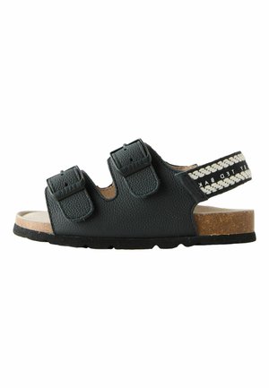 Black children's sandal with two adjustable buckles and a back strap with white braided pattern, cork footbed, and black sole.