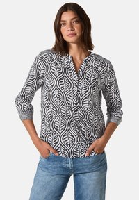 Blusa in bianco e nero con motivo a foglie, dotata di scollatura a V e maniche a tre quarti, arricchita da dettagli con bottoni.