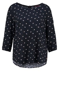 Blusa blu scuro con maniche a 3/4, scollo rotondo e piccoli motivi floreali bianchi. Tessuto morbido con orlo curvo e dettaglio a forma di chiave sul retro.