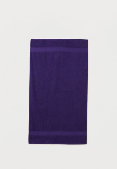 Σκούρο μωβ βαμβακερή πετσέτα μπάνιου με δύο οριζόντιες λωρίδες κοντά στις άνω και κάτω άκρες πάνω σε λευκό φόντο.