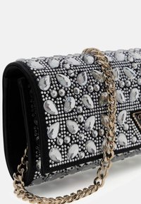 Borsa clutch nera decorata con cristalli trasparenti a goccia e rotondi, con tracolla a catena dorata e targhetta con logo triangolare.
