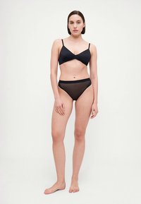 Ensemble bikini noir comprenant un haut bralette lisse à fines bretelles et un bas transparent à taille haute. Design simple, détails minimaux.