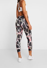 Legginsy z wysokim stanem, dopasowane do ciała, w abstrakcyjny wzór w kolorach czarnym, różowym i białym, charakteryzujące się gładką teksturą i długością do kostek.