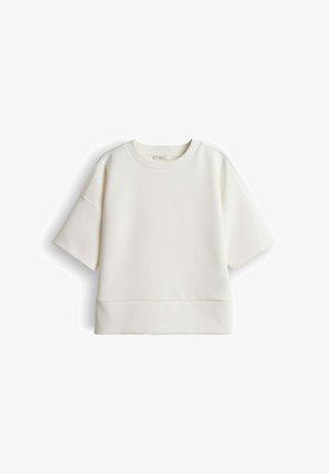 Sweat-shirt blanc à manches courtes avec col rond, coupe décontractée, et détail de couture au-dessus de l'ourlet, présenté sur un fond blanc uni.
