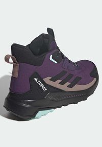 Purple hiking shoe with black accents, textured upper, and a sturdy rubber sole. Features a logo and a pull tab at the back for easy wear.