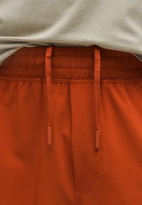 Orange sweatpants med en textured midja, med matchande dragkedjor och subtila sömnadsdetaljer. Mjuk tygfinish.