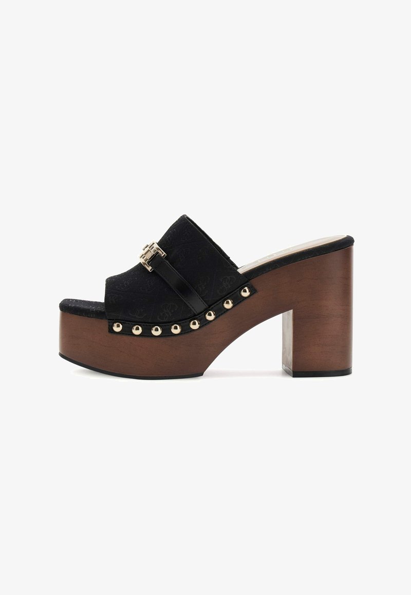 Mule plateforme noire à bout ouvert avec talon bloc en bois, clous dorés le long du bord de la semelle et boucle dorée décorative sur la bride supérieure.