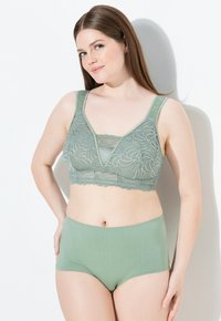 Groene kant bralette met een diepe V-hals en bredere banden, gecombineerd met bijpassende hoge taille slips. Zachte, gladde textuur, ingewikkeld patroon.