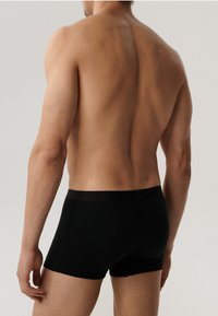 Czarne bawełniane bokserki z miękkim elastycznym paskiem, dopasowany krój i gładka faktura, prezentowane od tyłu na neutralnym tle.