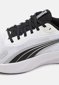 Weißer Sportschuh mit einem strukturierten Mesh-Obermaterial, schwarzen Akzenten, geschwungenen silbernen Details und einer gepolsterten weißen Sohle mit schwarzem Profil.